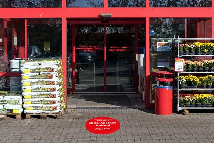 Abstandszonen im Außenbereich mit der runden Asphaltklebefolie mit Motiv Runde Asphaltklebefolie mit Motiv "Abstand halten" für Abstandszonen